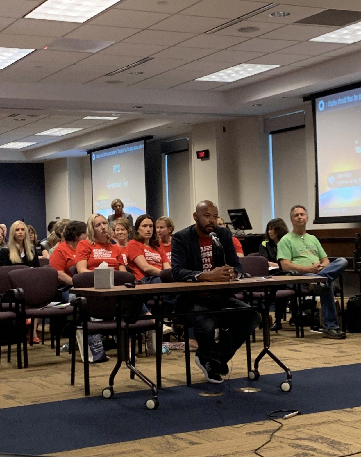 Khary Penebaker testifying for gun safety legislation with Moms Demand Action volunteers behind him